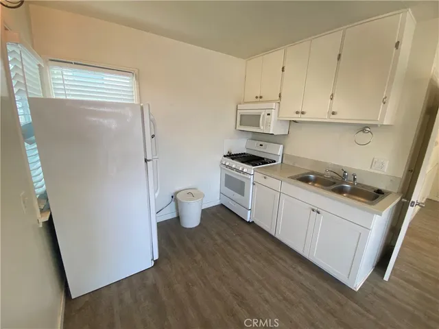 a kitchen with stainless steel appliances a refrigerator a stove a sink and white cabinets