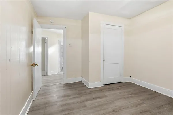 an empty room with wooden floor & closet area