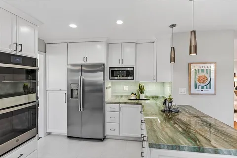 a kitchen with stainless steel appliances granite countertop a refrigerator and a stove top oven
