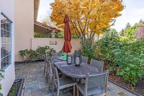 a view of a backyard with table and chairs potted plants and tree