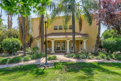 a view of a house with a yard and palm trees