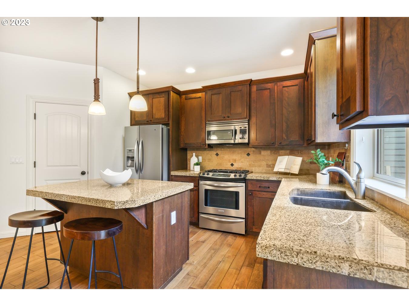 9277 Southwest Rambler Lane Portland, OR 97223 - Photo 9 of 38 a kitchen with stainless steel appliances granite countertop wooden cabinets a stove a sink and a microwave