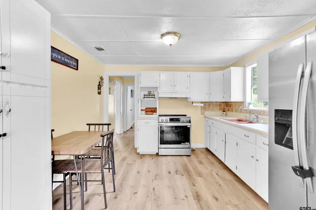a kitchen with stainless steel appliances a refrigerator sink and wooden floor