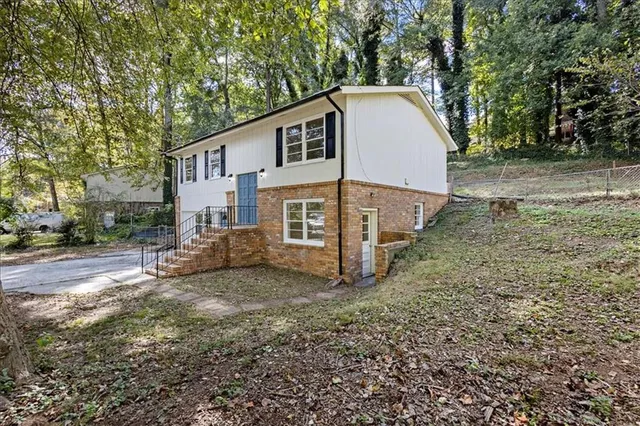 a view of a house with a yard and large tree