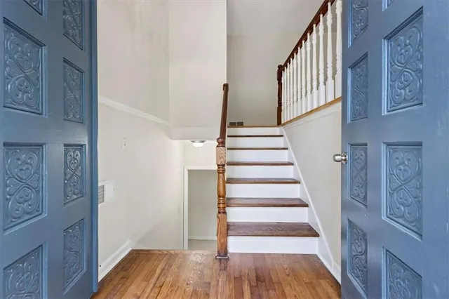a view of staircase with wooden floor and lots of frames on wall