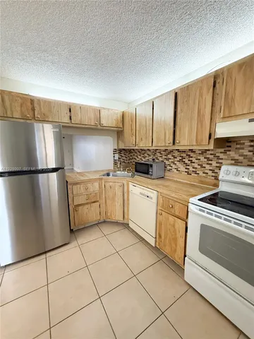 a kitchen with white cabinets a sink stove and a refrigerator