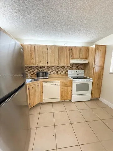 a white kitchen with a stove top oven and sink