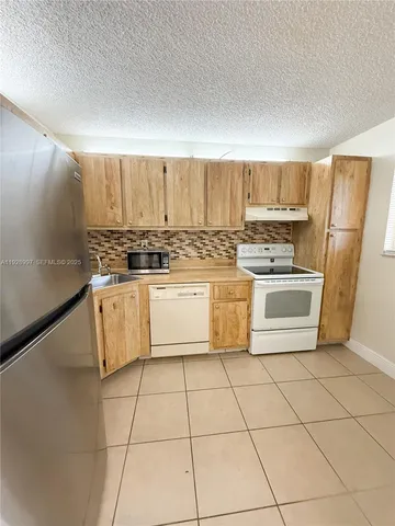 a white kitchen with a stove top oven and sink