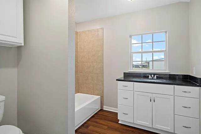 a bathroom with a granite countertop sink a toilet a mirror and bathtub