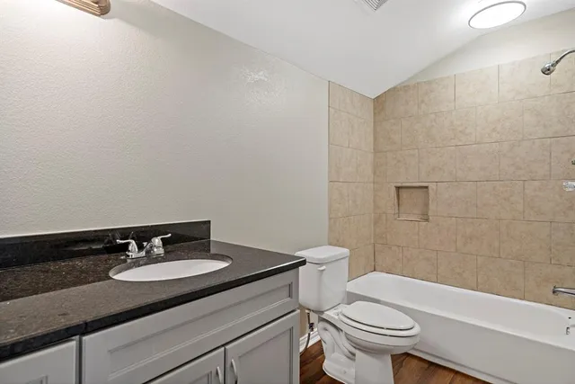 a bathroom with a granite countertop sink a toilet a mirror and bathtub