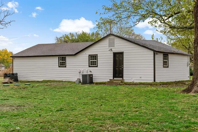 a backyard of a house with plants and a large tree
