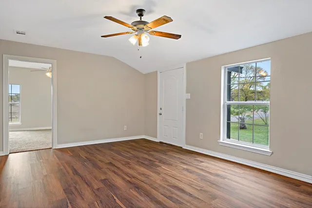 an empty room with wooden floor and windows