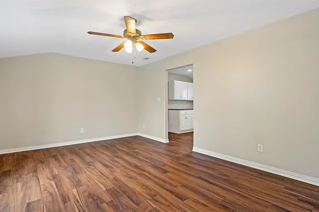 an empty room with wooden floor fan and windows
