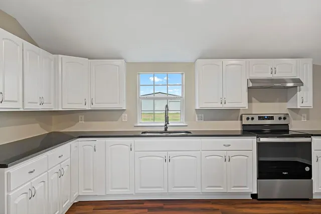 a kitchen with granite countertop white cabinets and stainless steel appliances