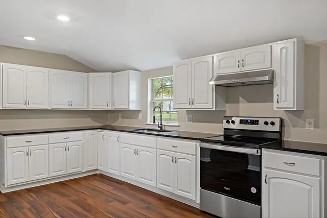 a kitchen with granite countertop white cabinets and stainless steel appliances