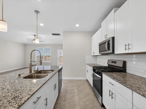 a kitchen with granite countertop a sink stainless steel appliances and cabinets