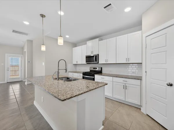 a kitchen with granite countertop a sink a counter top space appliances and cabinets