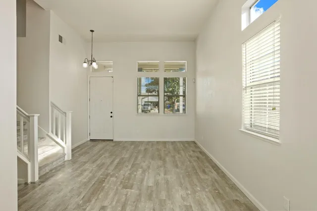 an empty room with wooden floor fan and windows