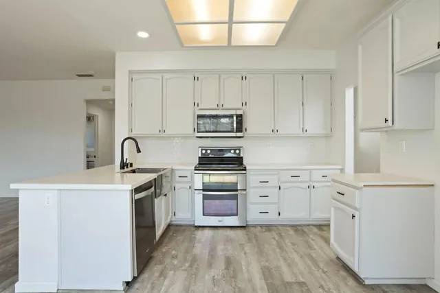 a kitchen with cabinets stainless steel appliances and sink