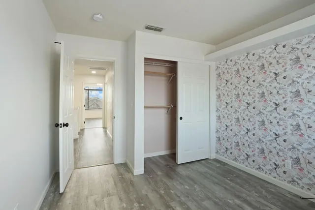 a view of a hallway with wooden floor and a bathroom
