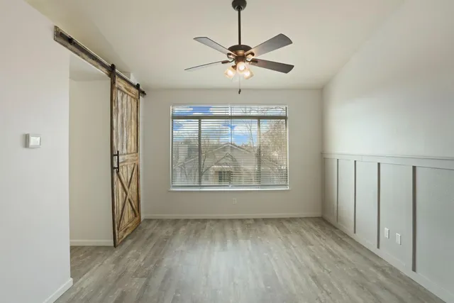 an empty room with wooden floor fan and windows