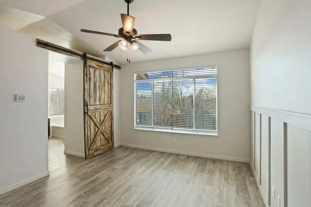 a view of an empty room with a window and wooden floor
