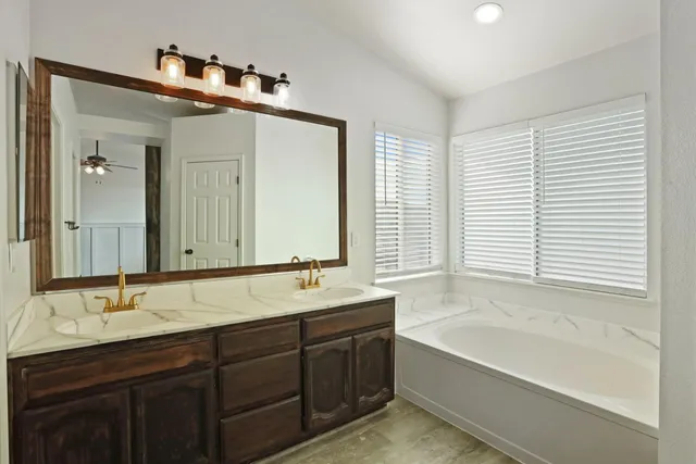 a bathroom with a tub a sink and a mirror