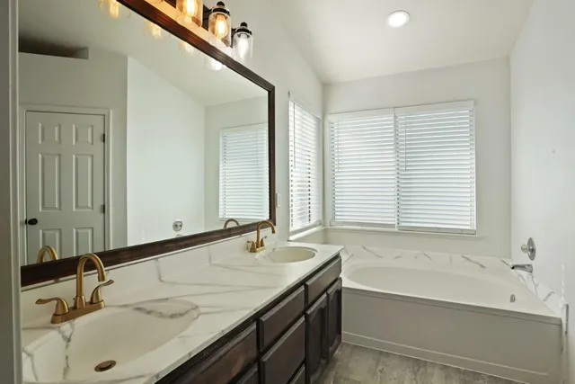 a bathroom with a granite countertop sink and a bathtub