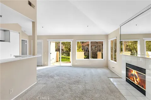 a view of an empty room with window and kitchen view