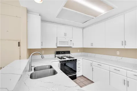 a kitchen with white cabinets a sink and white appliances