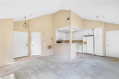 a view of a kitchen with refrigerator and white cabinets