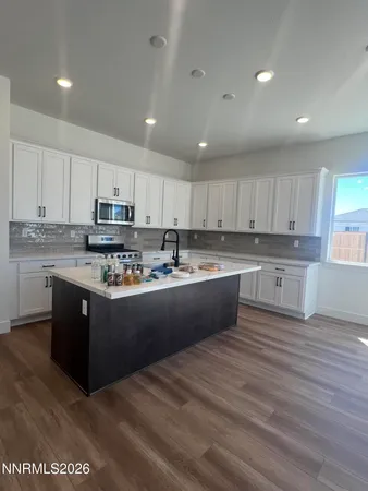 a large kitchen with stainless steel appliances granite countertop a stove a sink a refrigerator and white cabinets