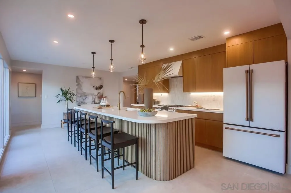 5878 Soledad Road La Jolla, CA 92037 - Photo 16 of 74 a kitchen with stainless steel appliances kitchen island a table chairs in it and wooden floors