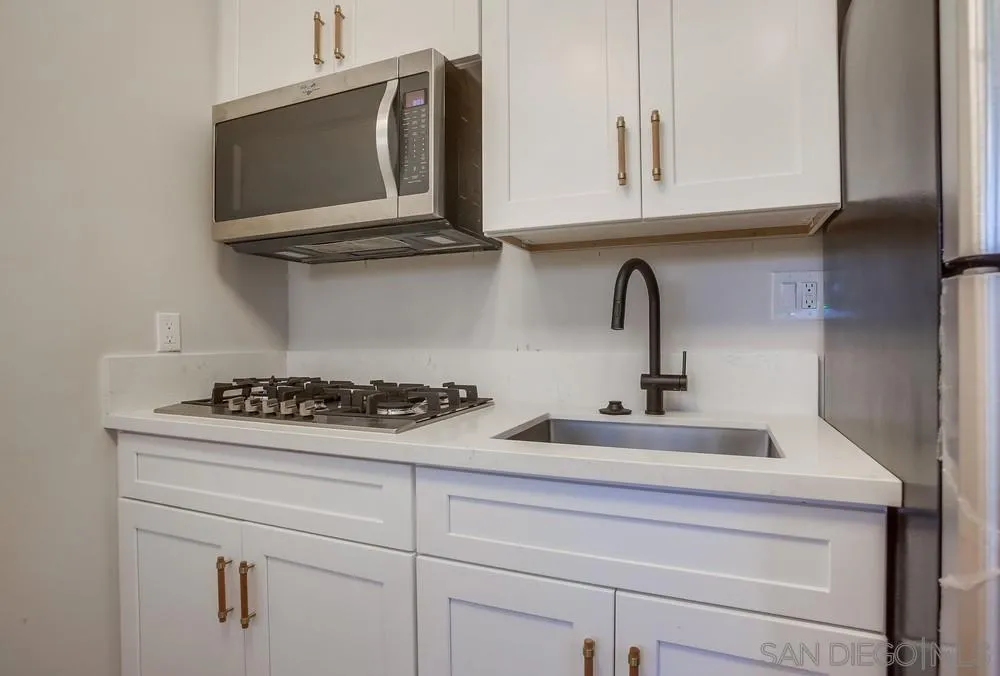 5878 Soledad Road La Jolla, CA 92037 - Photo 49 of 74 a kitchen with stainless steel appliances granite countertop white cabinets a stove a sink and dishwasher