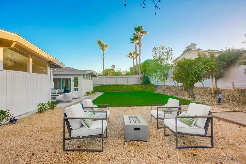 5878 Soledad Road La Jolla, CA 92037 - Photo 72 of 74 a view of a patio with table and chairs potted plants and a palm tree