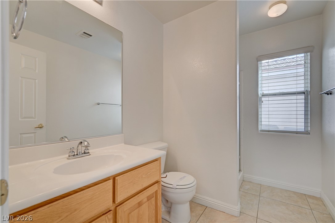 8918 Houston Ridge Avenue Las Vegas, NV 89178 - Photo 10 of 35 A pristine bathroom featuring a light wood vanity, a full-width mirror, and a tiled shower area.