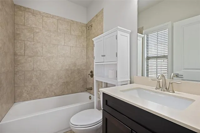 a bathroom with a bathtub shower sink vanity mirror and toilet
