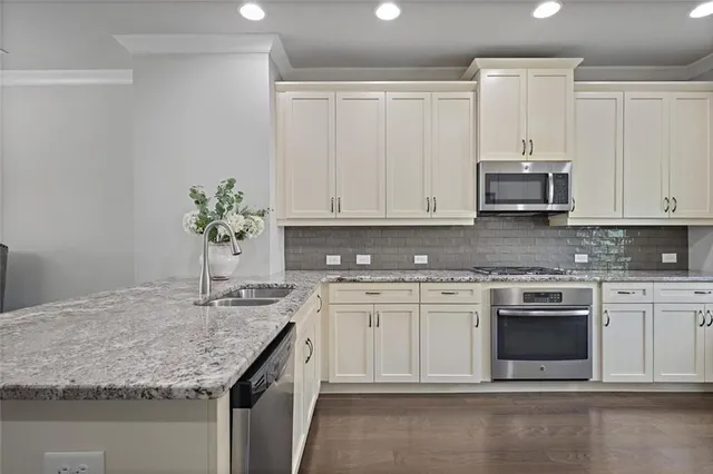 a kitchen with granite countertop a sink stainless steel appliances white cabinets and a granite counter tops