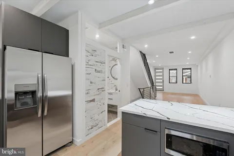 a bathroom with a granite countertop sink a refrigerator and a glass door
