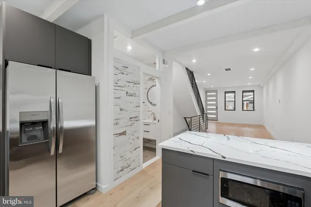 a bathroom with a granite countertop sink a refrigerator and a glass door