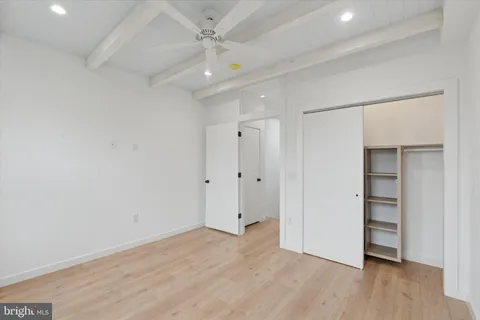 an empty room with wooden floor closet and windows