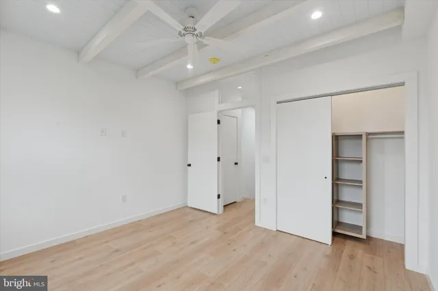 an empty room with wooden floor closet and windows