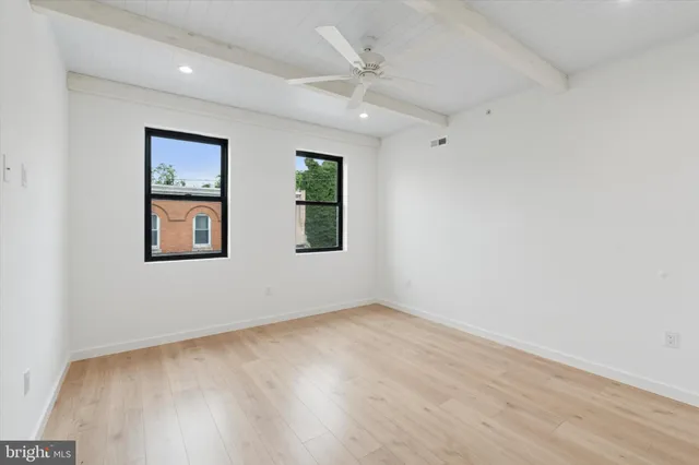an empty room with windows and ceiling fan