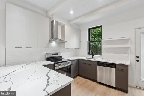 a kitchen with granite countertop stainless steel appliances sink stove and cabinets