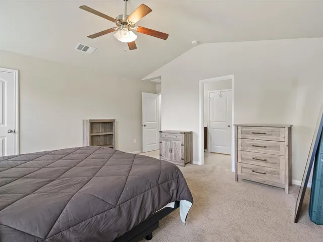 a spacious bedroom with a bed a dresser and a chandelier