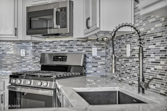 a kitchen with granite countertop white cabinets and stainless steel appliances