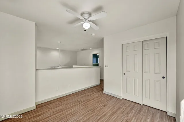 a view of empty room with wooden floor and ceiling fan