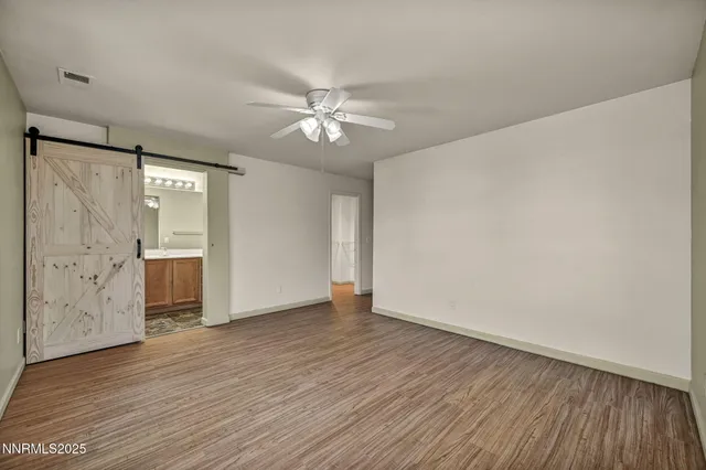 a view of empty room with wooden floor and fan