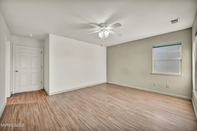 an empty room with wooden floor fan and windows