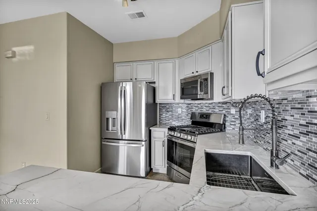 a kitchen with stainless steel appliances granite countertop a refrigerator sink and stove
